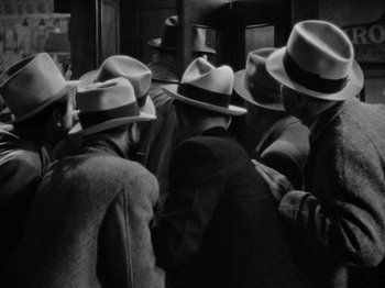 Movie still from “It Happened One Night” (1934), directed by Frank Capra – A black and white photo of a group of men wearing hats; Extreme Close Up shot, High angle