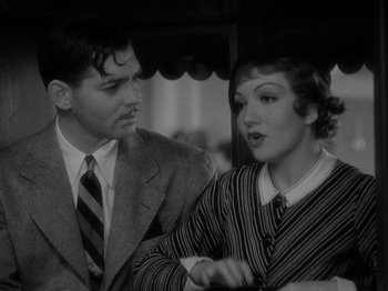 Movie still from “It Happened One Night” (1934), directed by Frank Capra – A man and a woman standing next to each other under an umbrella; Close Up shot, High angle