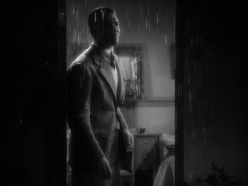 Movie still from “It Happened One Night” (1934), directed by Frank Capra – A black and white photo of a man standing in the rain; Medium shot, Low angle