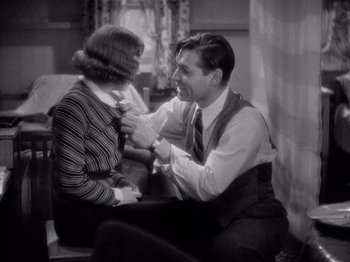 Movie still from “It Happened One Night” (1934), directed by Frank Capra – A man and a woman sitting on a chair and tying a neck tie; Medium shot, High angle