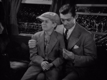 Movie still from “It Happened One Night” (1934), directed by Frank Capra – A man sitting next to a young boy on a bus; Medium shot, High angle