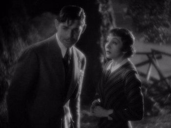 Movie still from “It Happened One Night” (1934), directed by Frank Capra – A man and a woman standing next to each other in front of trees; Medium shot, High angle