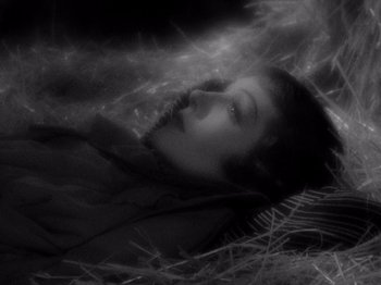 Movie still from “It Happened One Night” (1934), directed by Frank Capra – A black - and - white photo of a woman laying in a field; Close Up shot, Overhead angle