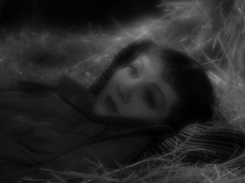 Movie still from “It Happened One Night” (1934), directed by Frank Capra – A young woman laying in a bed with a blanket; Close Up shot, Overhead angle