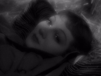 Movie still from “It Happened One Night” (1934), directed by Frank Capra – A woman laying in a bed with her eyes closed; Extreme Close Up shot, Overhead angle