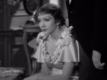 Movie still from “It Happened One Night” (1934), directed by Frank Capra – A woman sitting in a chair wearing a lei; Close Up shot, High angle