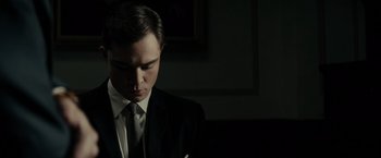 Movie still from “J. Edgar” (2011), directed by Clint Eastwood – A man wearing a suit and tie in a dark room; Close Up shot, Low angle