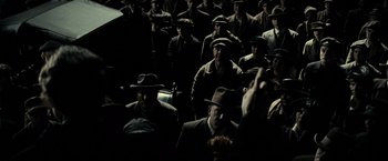 Movie still from “J. Edgar” (2011), directed by Clint Eastwood – A group of men in suits and hats sitting in a dark room; Wide shot, High angle