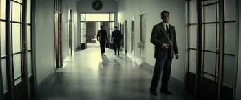 Movie still from “J. Edgar” (2011), directed by Clint Eastwood – A man in a suit and tie standing in a hallway; Wide shot, Low angle
