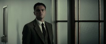 Movie still from “J. Edgar” (2011), directed by Clint Eastwood – A man in a suit and tie standing in front of a window; Medium shot, Low angle
