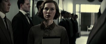 Movie still from “J. Edgar” (2011), directed by Clint Eastwood – A woman in a brown and white dress holding a book; Close Up shot, Low angle