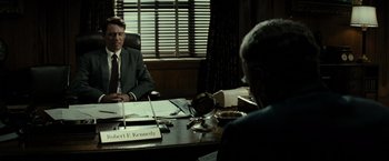 Movie still from “J. Edgar” (2011), directed by Clint Eastwood – Two people sitting at a desk in a room; Medium shot, Over the shoulder angle