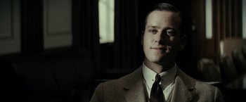 Movie still from “J. Edgar” (2011), directed by Clint Eastwood – A man wearing a suit and tie sitting in front of a window; Close Up shot, Low angle
