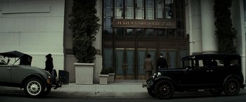 Movie still from “J. Edgar” (2011), directed by Clint Eastwood – Two men in suits and a car in front of julius gareinke & company; Extreme Wide shot, Low angle
