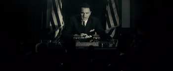Movie still from “J. Edgar” (2011), directed by Clint Eastwood – A black and white photo of a man sitting at a table; Medium shot, Low angle