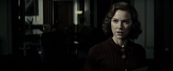 Movie still from “J. Edgar” (2011), directed by Clint Eastwood – A woman in a brown sweater standing in a dark room; Close Up shot, Over the shoulder angle