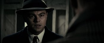 Movie still from “J. Edgar” (2011), directed by Clint Eastwood – A person wearing a suit and a hat; Close Up shot, Over the shoulder angle