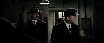 Movie still from “J. Edgar” (2011), directed by Clint Eastwood – Two men in suits and hats are standing in a room; Medium shot, Low angle