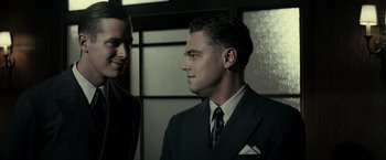 Movie still from “J. Edgar” (2011), directed by Clint Eastwood – A man in a suit and tie standing next to another man in a suit and tie; Close Up shot, Low angle