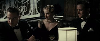 Movie still from “J. Edgar” (2011), directed by Clint Eastwood – A woman sitting at a table with a glass of wine in front of her; Medium shot, Over the shoulder angle