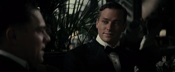 Movie still from “J. Edgar” (2011), directed by Clint Eastwood – A man in a suit and bow tie in front of a plant; Close Up shot, Over the shoulder angle