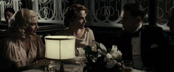 Movie still from “J. Edgar” (2011), directed by Clint Eastwood – A woman sitting at a table with a lamp in front of her; Medium shot, Over the shoulder angle