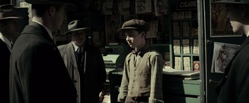 Movie still from “J. Edgar” (2011), directed by Clint Eastwood – A man in a hat and a tie standing next to a man in a suit; Medium shot, Over the shoulder angle