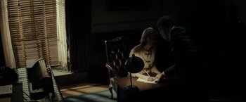 Movie still from “J. Edgar” (2011), directed by Clint Eastwood – A man and a woman sitting at a desk in the dark; Medium shot, High angle