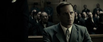 Movie still from “J. Edgar” (2011), directed by Clint Eastwood – A man in a suit and tie in front of a group of people; Close Up shot, Low angle
