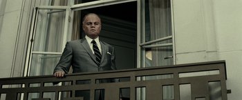 Movie still from “J. Edgar” (2011), directed by Clint Eastwood – A man in a suit and tie standing in front of a window; Medium shot, Low angle
