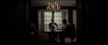 Movie still from “J. Edgar” (2011), directed by Clint Eastwood – Two men sitting at a table in a dark room; Wide shot, Low angle