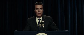 Movie still from “J. Edgar” (2011), directed by Clint Eastwood – A man in a suit and tie at a podium; Close Up shot, Over the shoulder angle