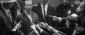 Movie still from “JFK” (1991), directed by Oliver Stone – A group of men holding microphones in front of each other; Close Up shot, Over the shoulder angle
