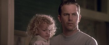 Movie still from “JFK” (1991), directed by Oliver Stone – A man and a little girl standing next to each other; Close Up shot, Low angle