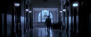 Movie still from “JFK” (1991), directed by Oliver Stone – A person walking down a hall way in a building; Extreme Wide shot, Low angle