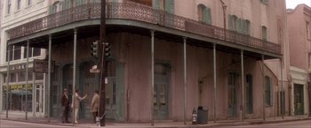 Movie still from “JFK” (1991), directed by Oliver Stone – A man walking down the sidewalk in front of a building; Extreme Wide shot, Low angle