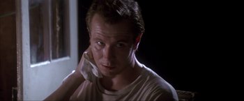 Movie still from “JFK” (1991), directed by Oliver Stone – A person wearing a white t - shirt; Close Up shot, Low angle