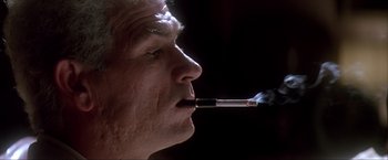 Movie still from “JFK” (1991), directed by Oliver Stone – A person smoking a cigarette; Extreme Close Up shot, Low angle