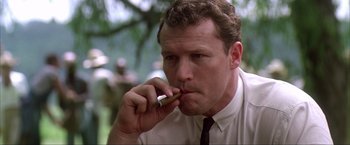 Movie still from “JFK” (1991), directed by Oliver Stone – A person with a cigarette in his mouth; Close Up shot, Low angle