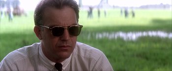 Movie still from “JFK” (1991), directed by Oliver Stone – A person wearing sunglasses and a tie; Close Up shot, Low angle