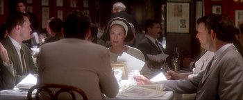 Movie still from “JFK” (1991), directed by Oliver Stone – A woman sitting at a dinner table with a man; Medium shot, Over the shoulder angle