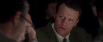 Movie still from “JFK” (1991), directed by Oliver Stone – A person wearing a suit and tie; Close Up shot, Over the shoulder angle