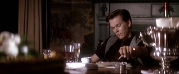 Movie still from “JFK” (1991), directed by Oliver Stone – A man sitting at a table with a plate in front of him; Medium shot, Low angle