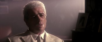 Movie still from “JFK” (1991), directed by Oliver Stone – An older man in a white suit and tie; Close Up shot, Low angle