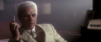 Movie still from “JFK” (1991), directed by Oliver Stone – A man in a suit and tie sitting down; Close Up shot, Low angle