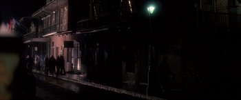 Movie still from “JFK” (1991), directed by Oliver Stone – A street light lit up at night on a rainy night; Extreme Wide shot, High angle