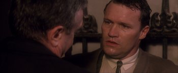 Movie still from “JFK” (1991), directed by Oliver Stone – A man in a suit and tie looking at another man in a suit and tie; Close Up shot, Over the shoulder angle
