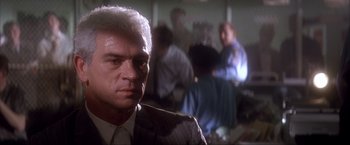 Movie still from “JFK” (1991), directed by Oliver Stone – A man in a suit and tie in a room; Close Up shot, Low angle