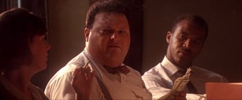 Movie still from “JFK” (1991), directed by Oliver Stone – A person smoking a cigarette; Close Up shot, Low angle