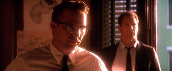 Movie still from “JFK” (1991), directed by Oliver Stone – A person wearing glasses and a tie; Close Up shot, Low angle